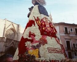 a large christmas tree made of flowers in front of a building